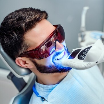 Man in dental chair receiving teeth whitening