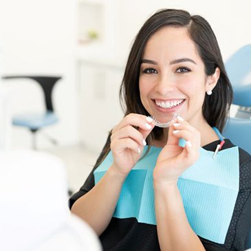 Happy dental patient holding Invisalign aligner