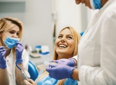Woman in dental chair laughing with her dentist in Allen